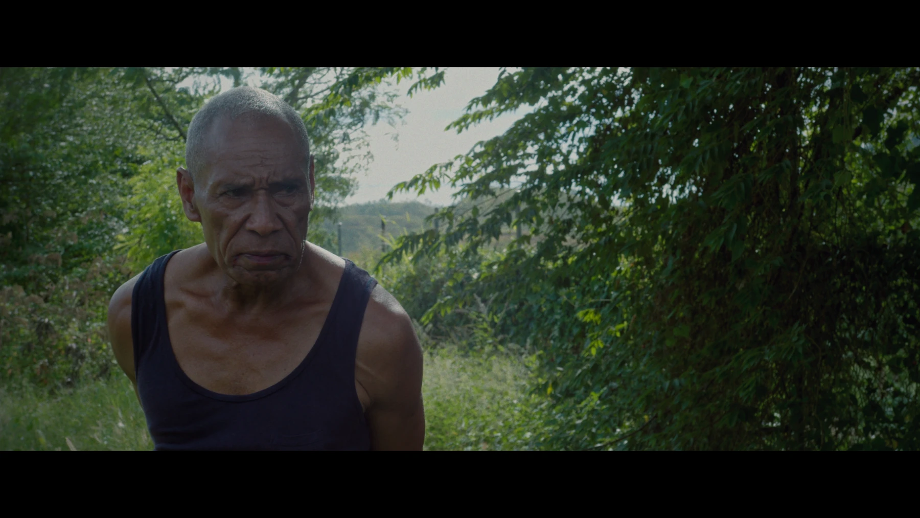 Film still: a character on a tropical pathway